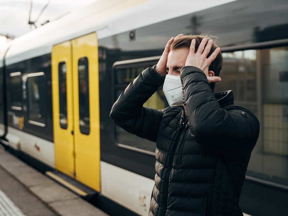 Mann vor einem Zug schlägt sich die Hände an den Kopf.