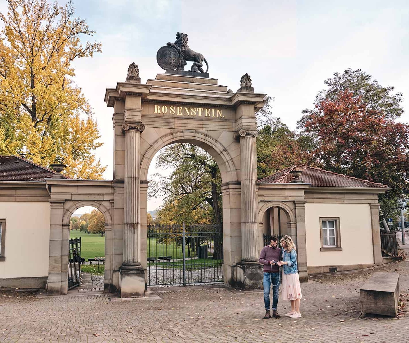 Ein Paar steht vor dem Rosensteinpark in Stuttgart.