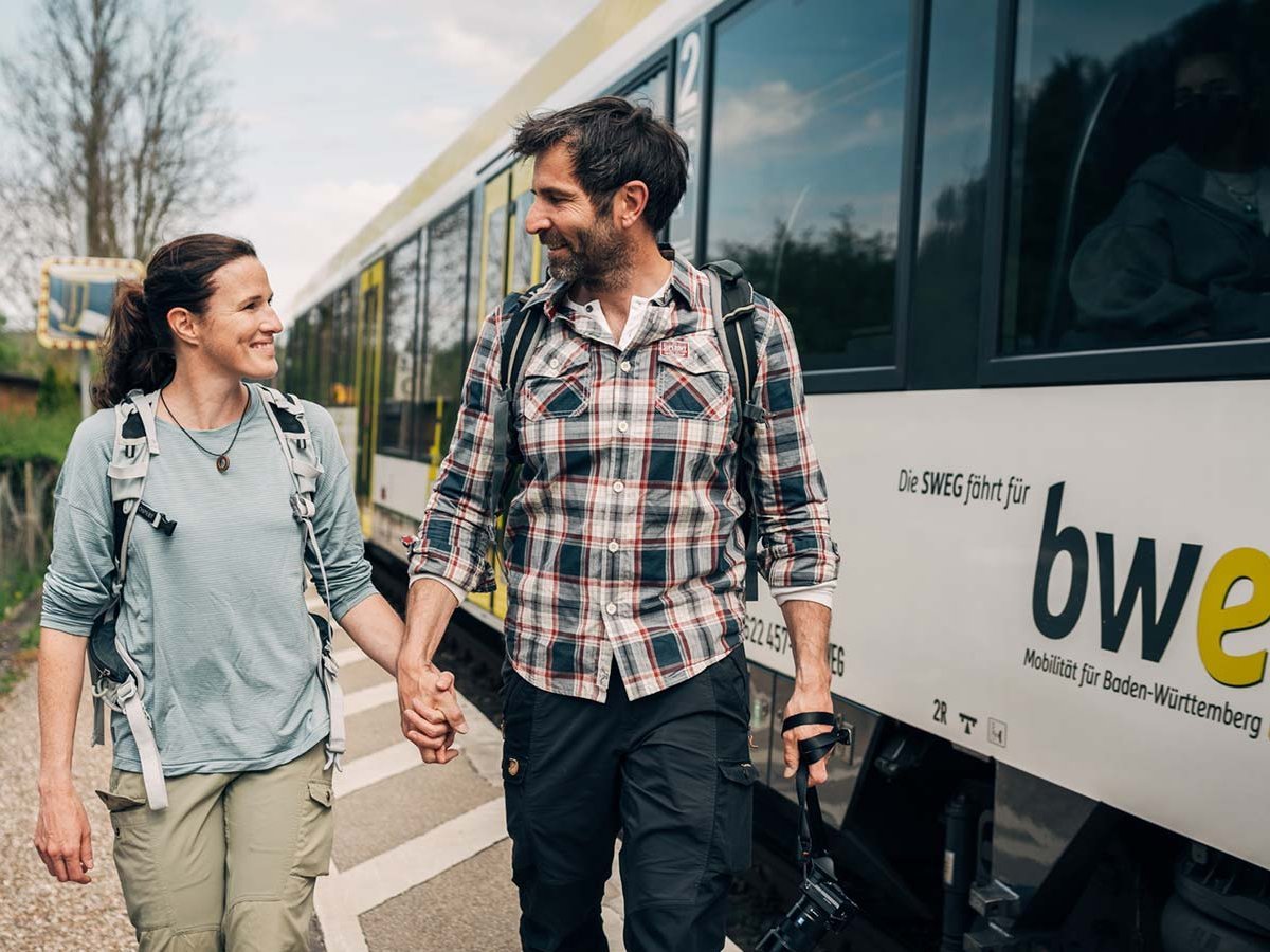 Paar läuft Hand in Hand am Bahnsteig entlang.