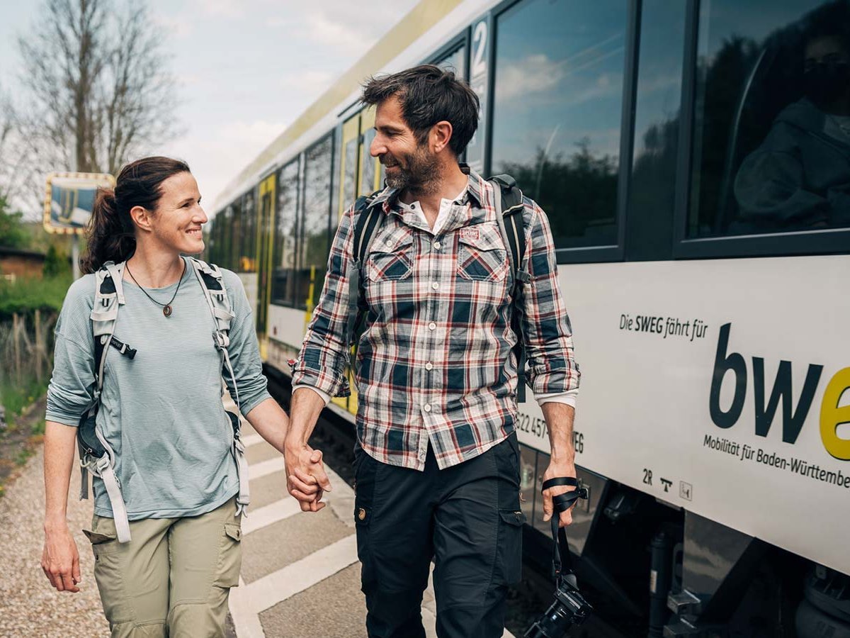 Paar läuft Hand in Hand den Bahnsteig entlang.