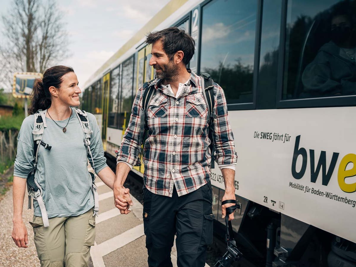 Päärchen läuft Hand in Hand den Bahnsteig entlang.