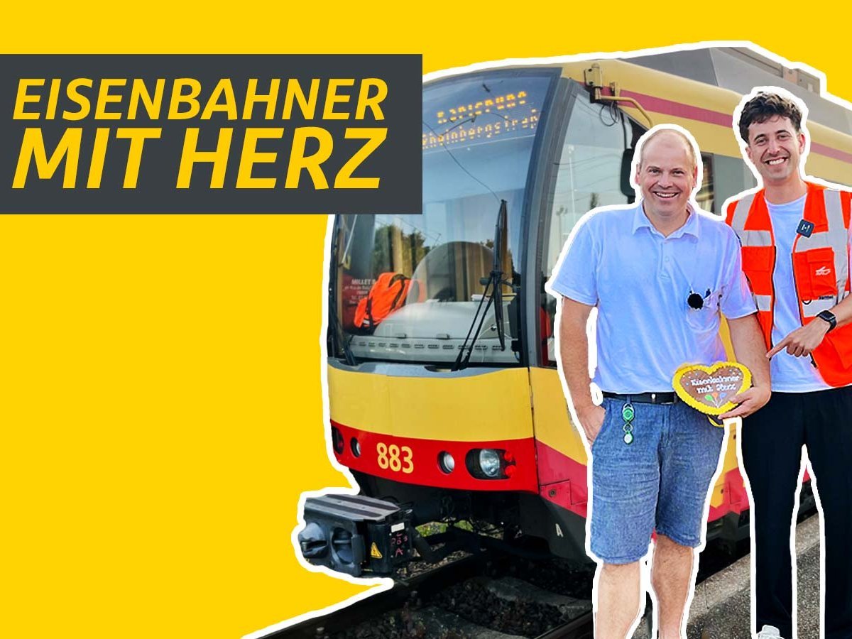 Junger Mann steht neben einem Lokführer vor einer Straßenbahn.