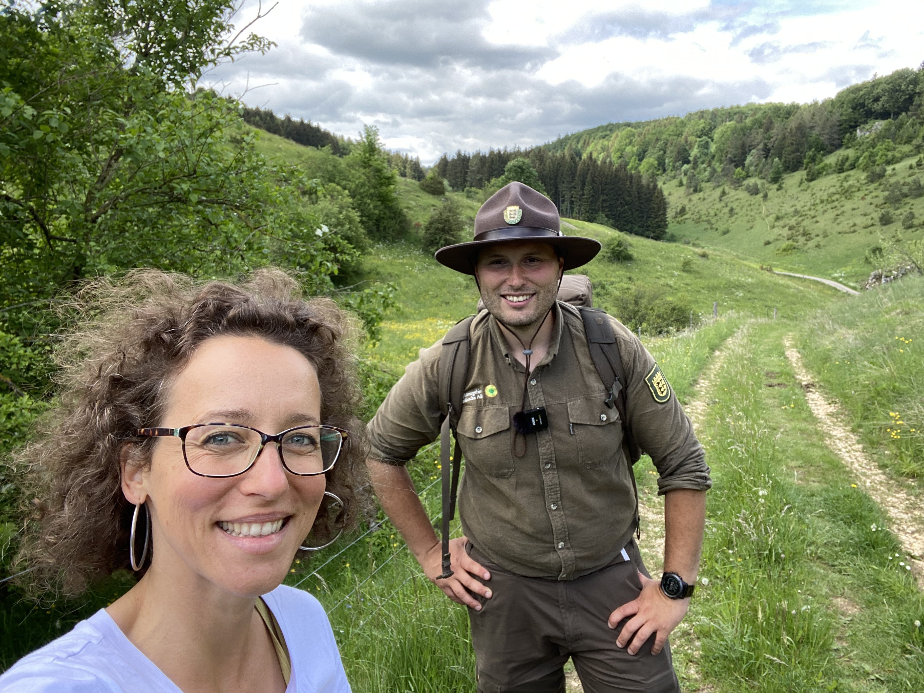 Frau steht mit Ranger in der Natur.