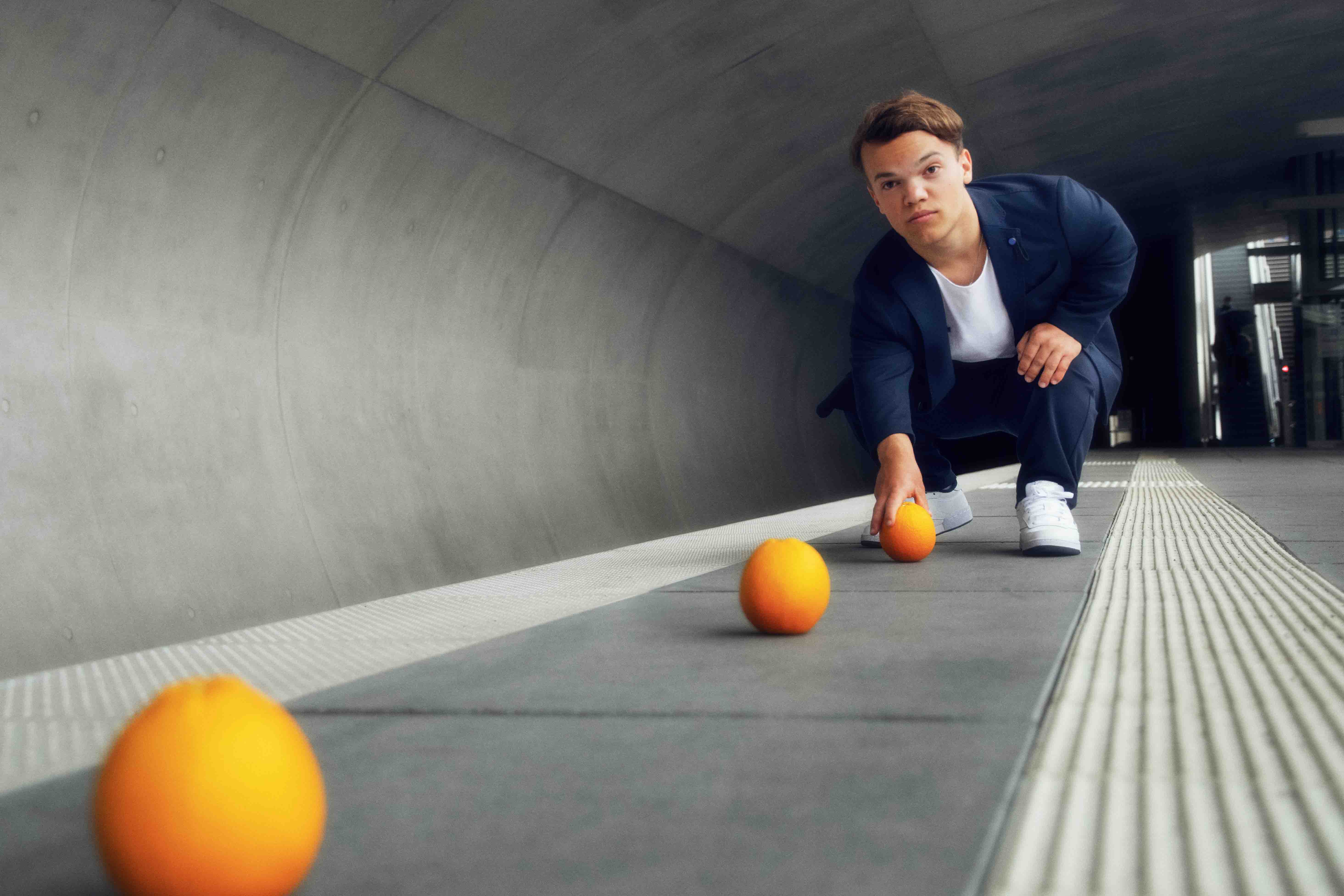 Ein junger Mann auf dem Bahnsteig legt Orangen aus