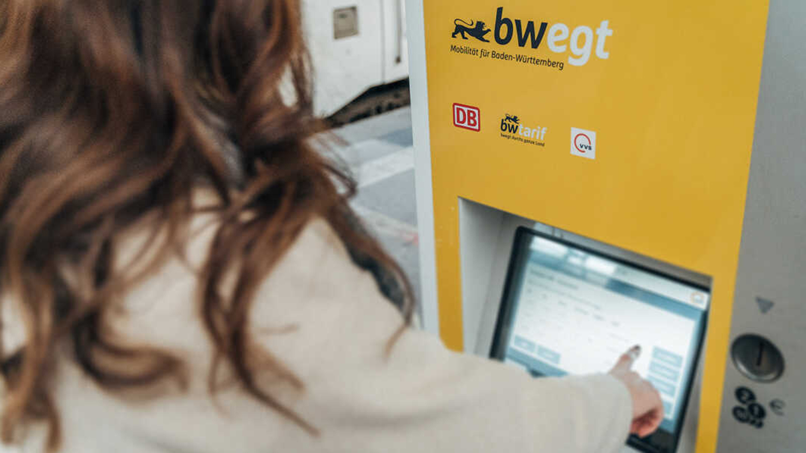Eine Frau tippt auf den Bildschirm eines Ticket-Automats