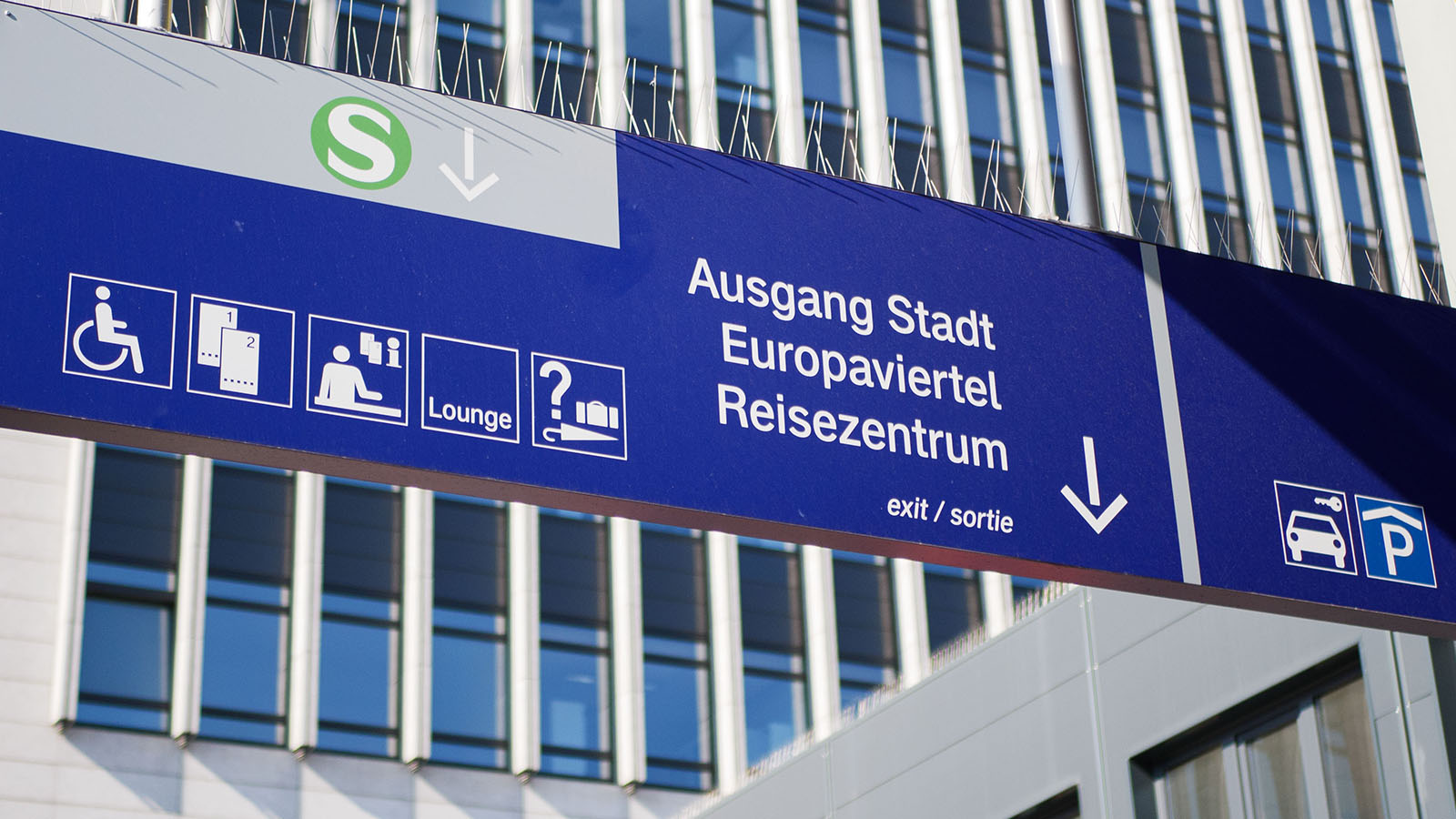 Ein blaues Schild im Bahnhof zeigt den Ausgang in Richtung Stadt, Europaviertel und Reisezentrum