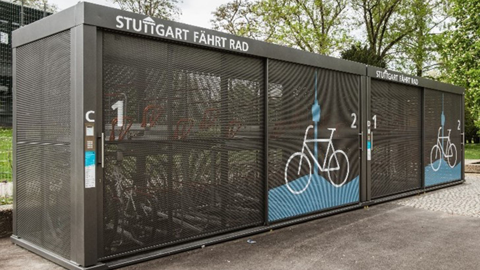 Eine Fahrradsammelanlage mit Fahrrad-Symbolen in einem Park mit der Aufschrift Stuttgart fährt Rad