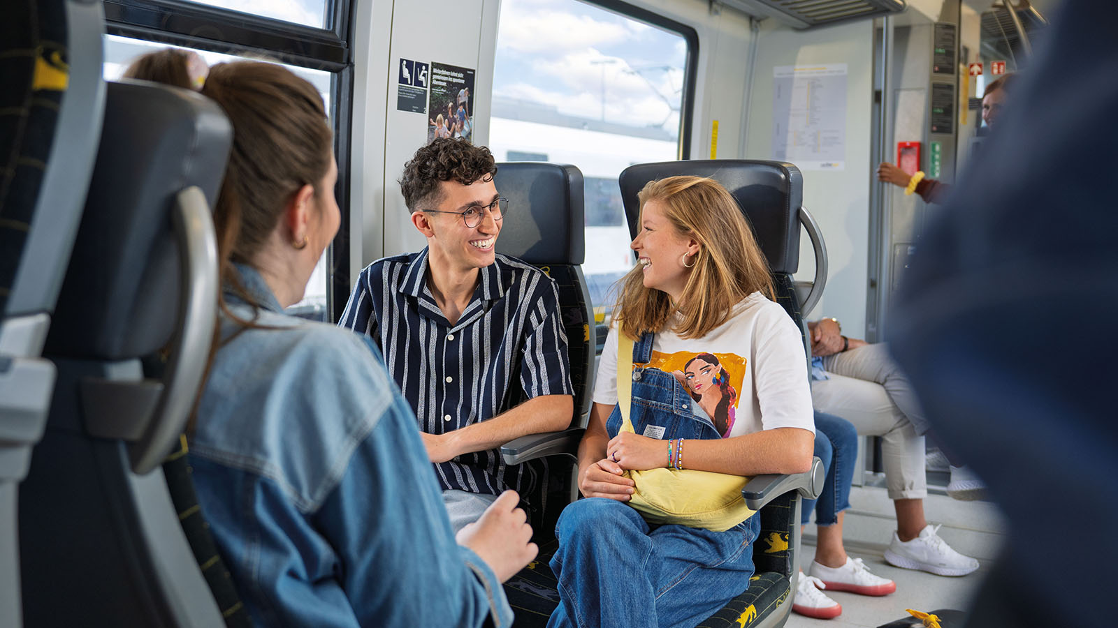 Ein junger Mann und Frau unterhalten sich auf der Fahrt in einem Zug.