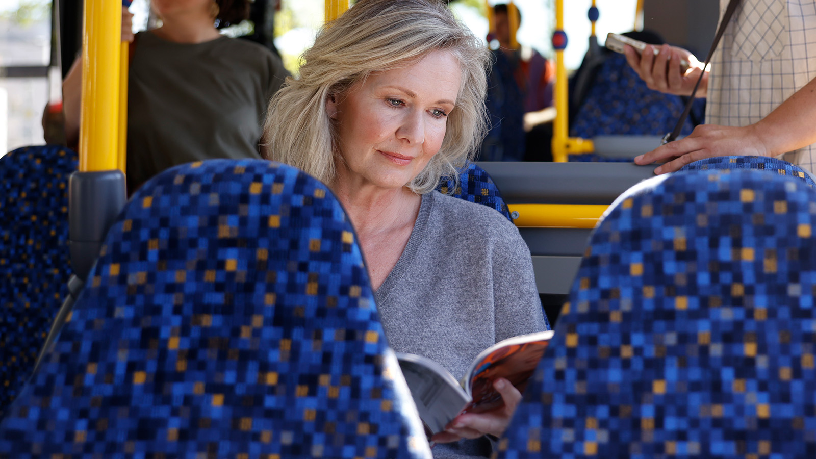 Eine Frau liest in einem Bus ein Prospekt.