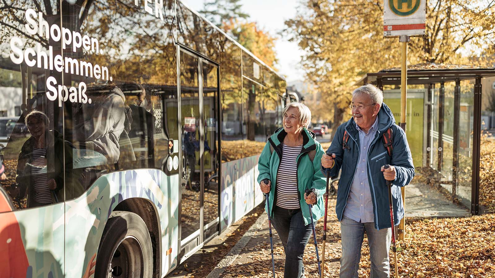 Eine Frau und ein Mann laufen an einem Bus vorbei