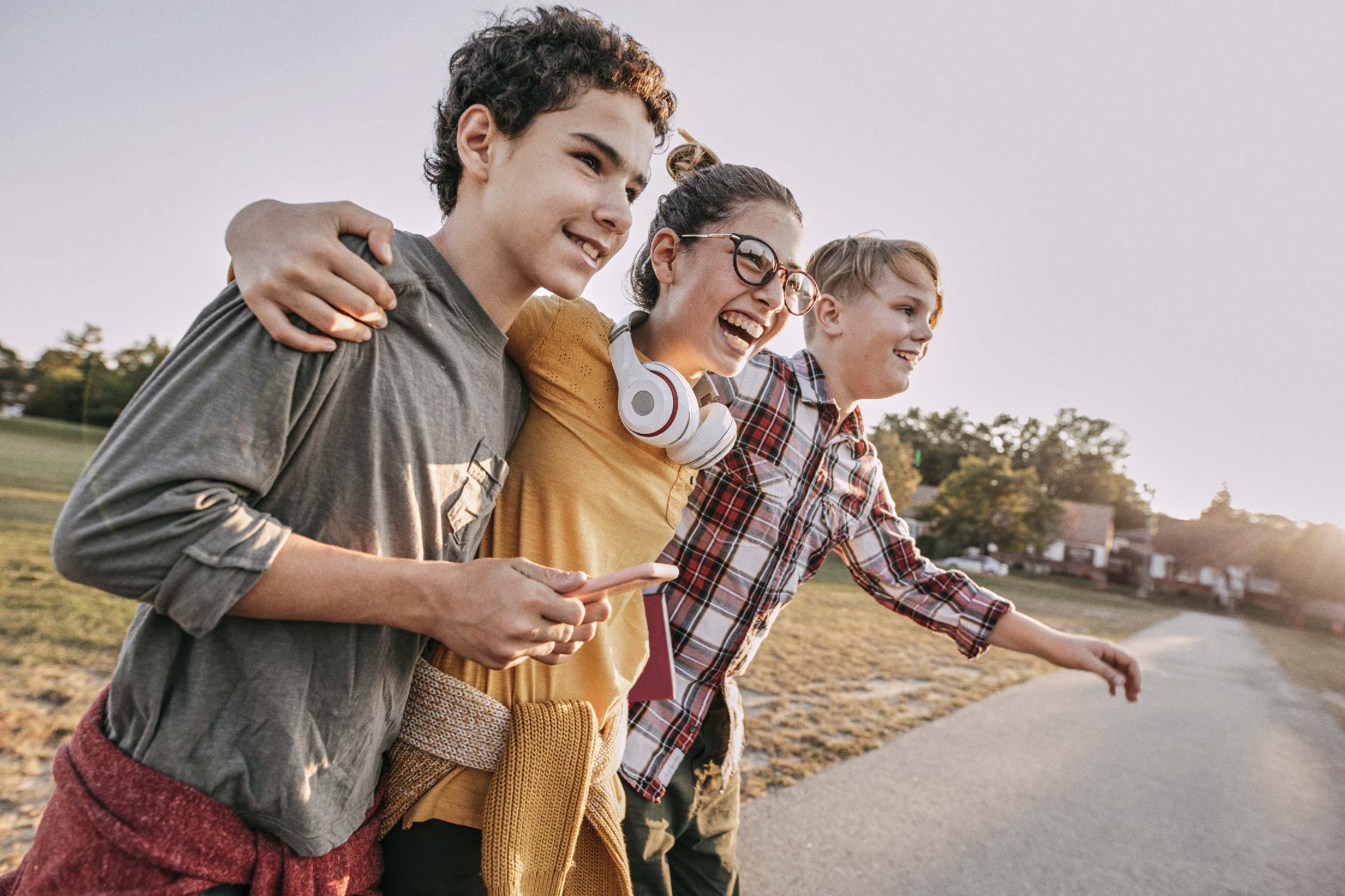 Drei Teenager, einer von ihnen hat ein Smartphone in der Hand