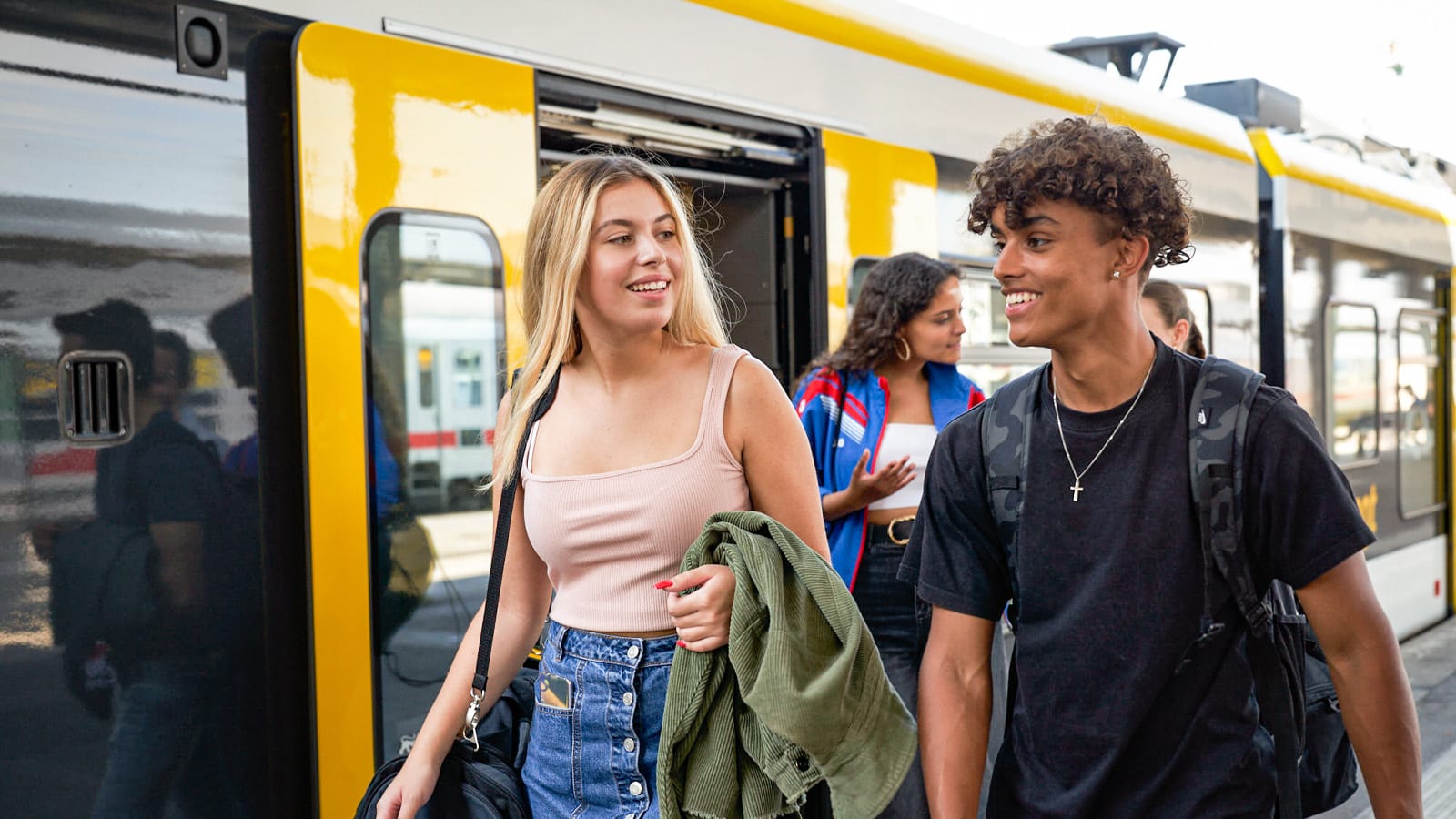 Zwei junge Menschen steigen am Bahnhof aus dem Zug