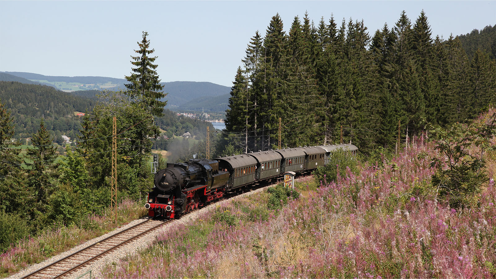 Eine Dampflokomotive fährt durch einen idyllischen Gebirgspass