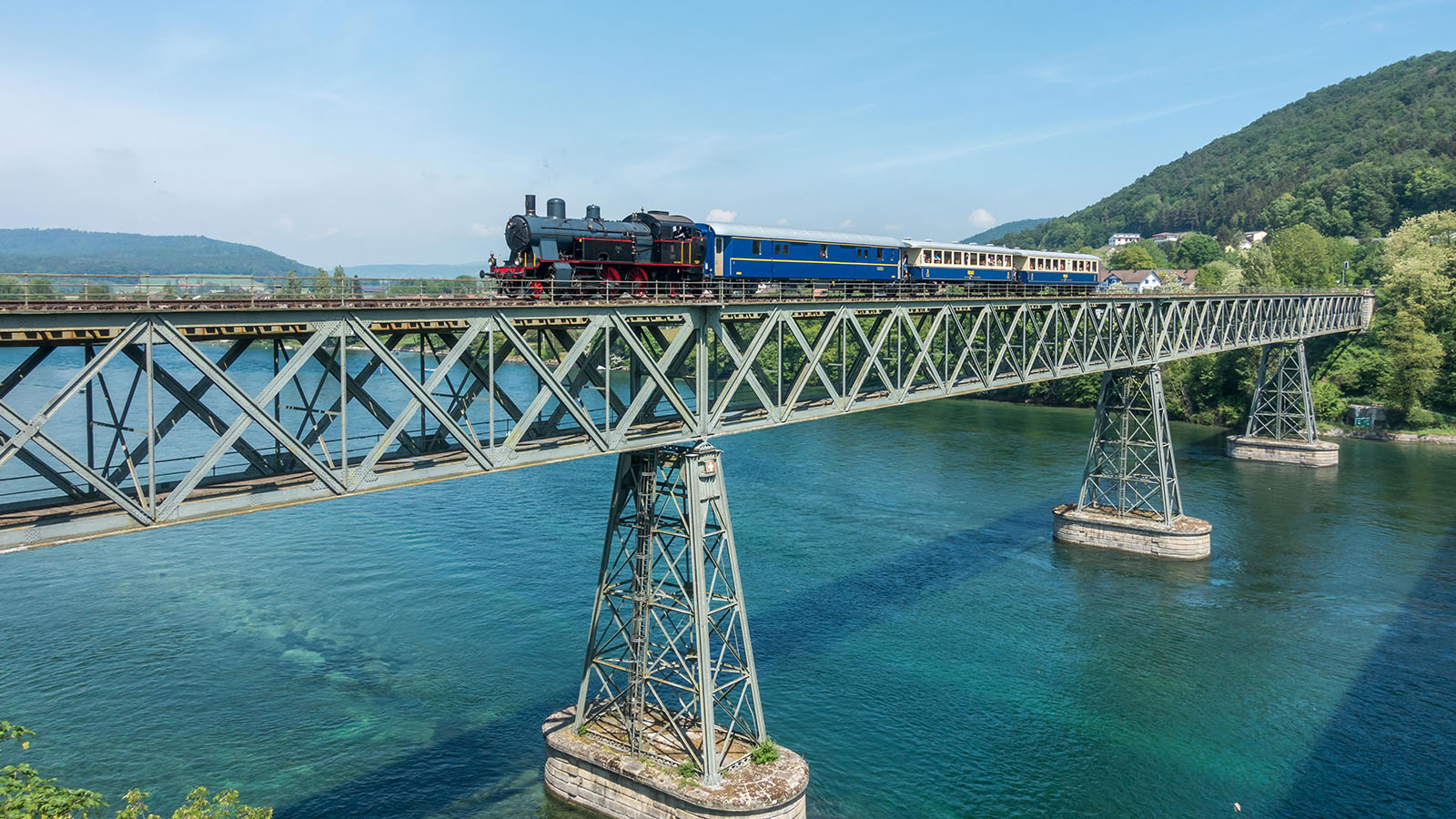 Eine Eisenbahnbrücke, die über einen blauen See führt