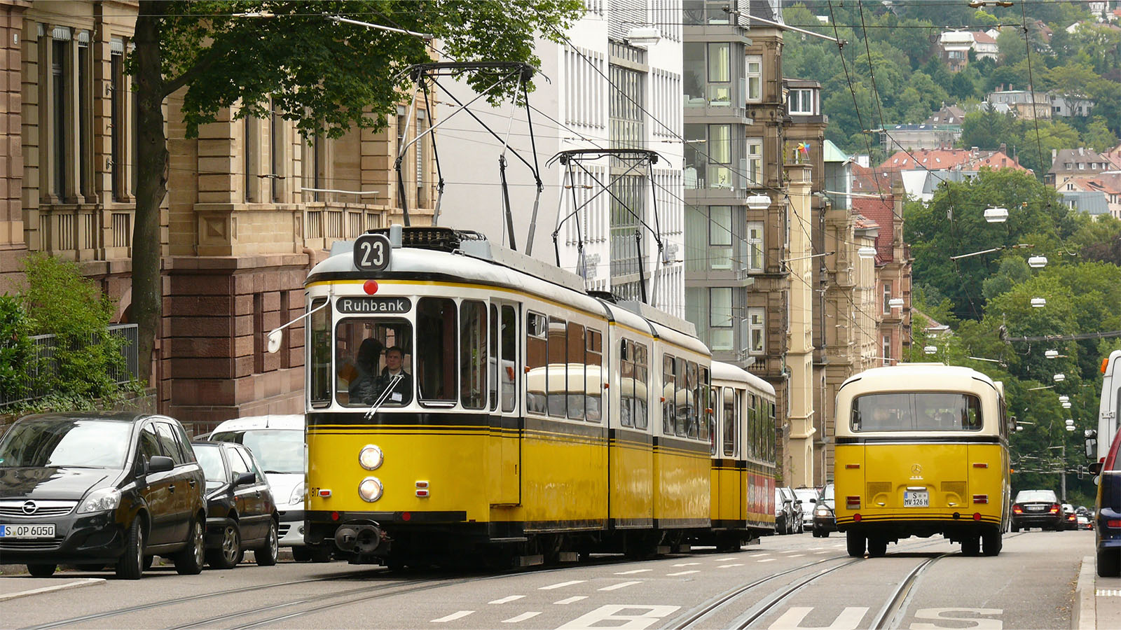 Eine gelbe, historische Straßenbahn im Stuttgarterverkehr neben einem historischen, gelben Auto