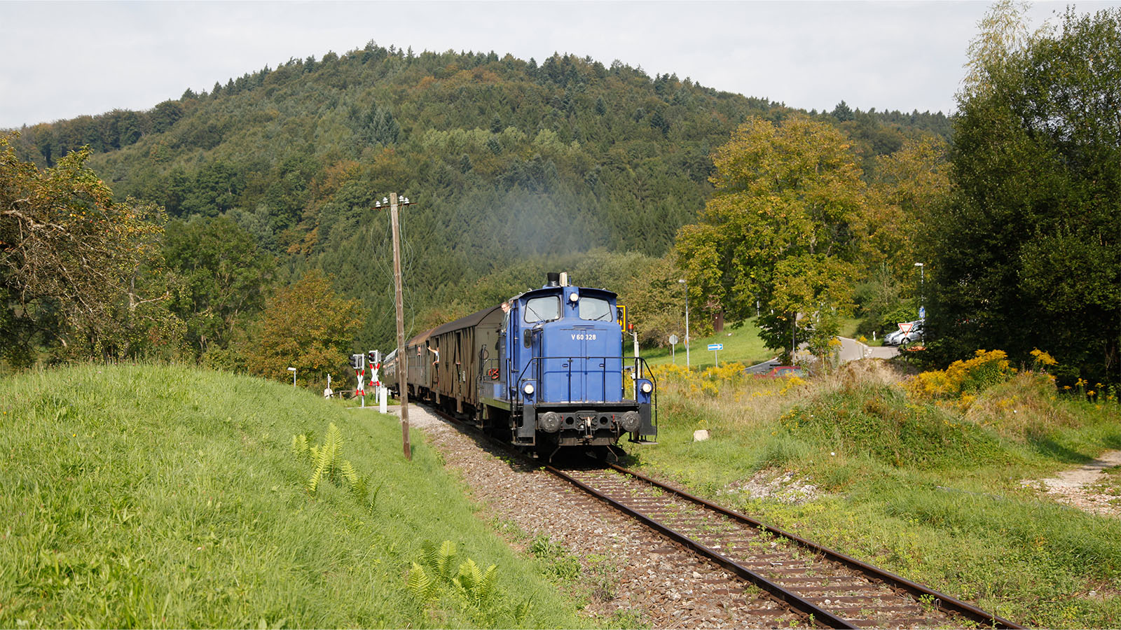 Blaue, historische Bahn, die durch eine unbesiedelte, grüne Gebirgslandschaft fährt