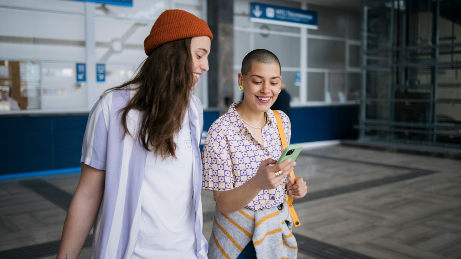 Zwei Personen am Bahnhof schauen auf ein Smartphone.