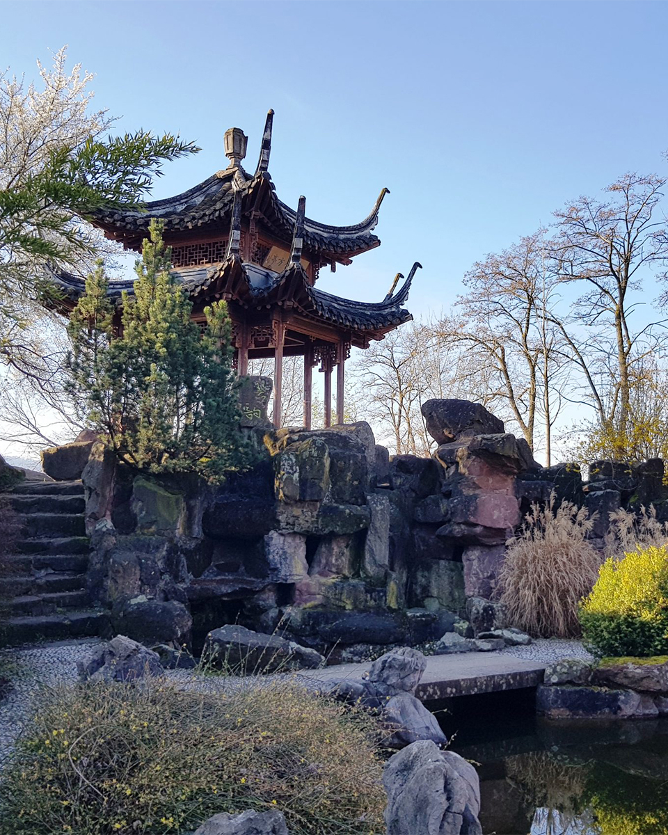 Blick in Chinesischen Garten: Eine kleine Pagode steht zwischen Felsen.