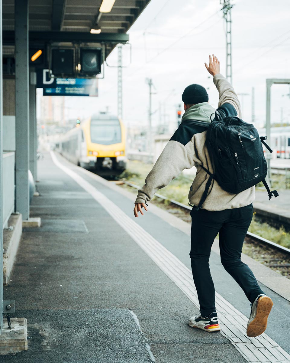 Mann rennt einer abfahrenden Bahn hinterher.