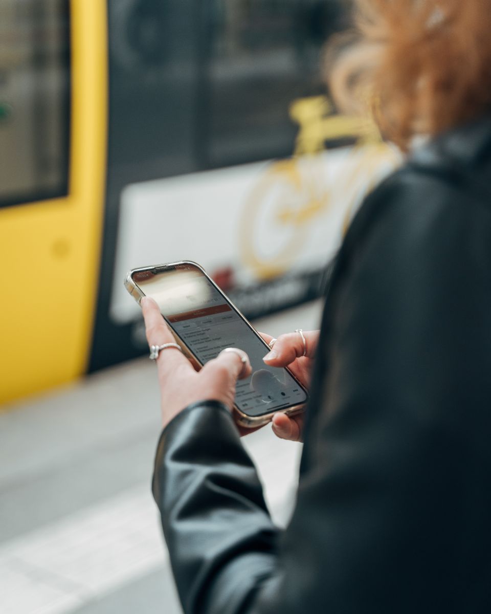 Blick über die Schulter einer Frau, die am Smartphone gerade die Navigator-App bedient.