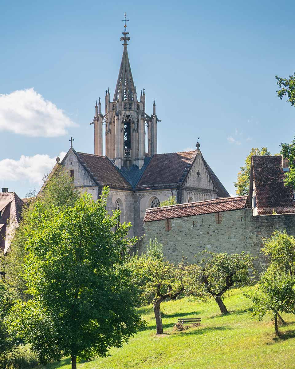 Klosterdach ist über eine Mauer hinweg zu sehen..