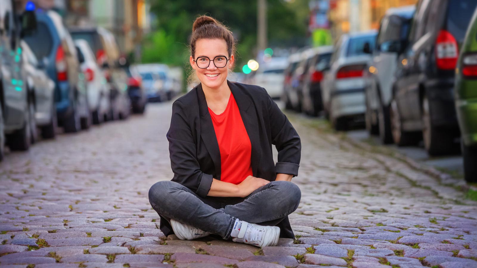 Frau sitzt im Schneidersitz auf der Straße.