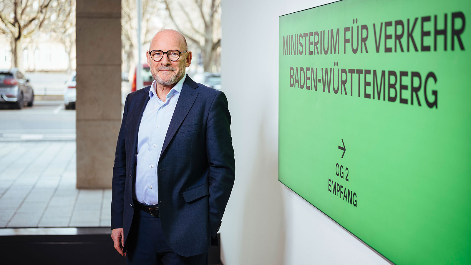 Verkehrsminister Hermann steht im Ministerium vor einer grünen Tafel.