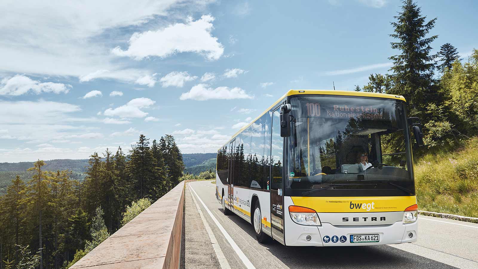 Auf einer Landstraße fährt ein Bus in den bwegt-Farben.