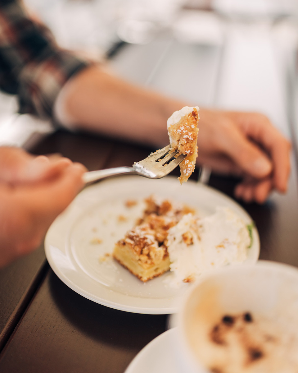 Person mit einem Stück Kuchen auf der Gabel.