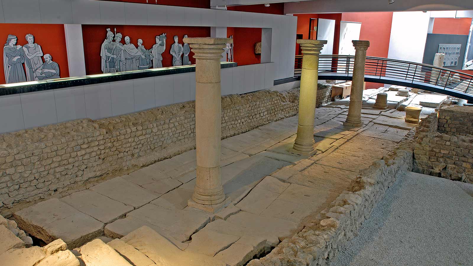 Innenaufnahme aus dem römischen Stadtmuseum Summelocenna in Rottenburg am Neckar. Die Aufnahme zeigt entlang einer Säulenreihe die antiken Überreste einer alten römischen Latrine. 