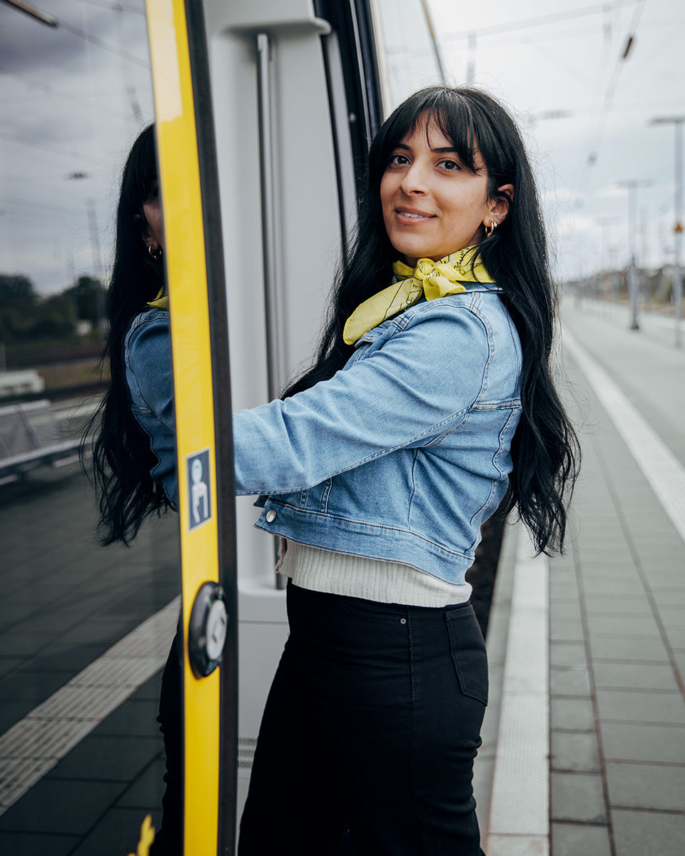 Eine junge Frau steigt lächelnd in einen Regionalzug im bwegt-Design ein.  