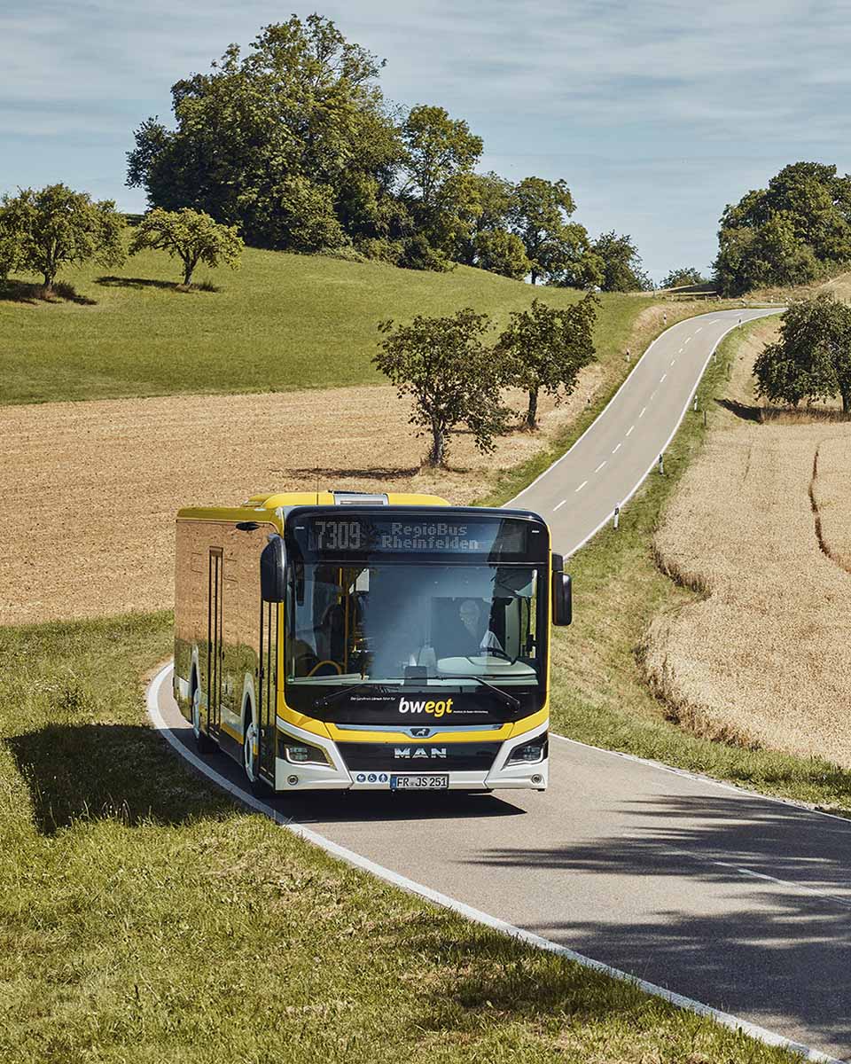 Ein Regiobus im bwegt-Design fährt auf einer einsamen Landstraße.