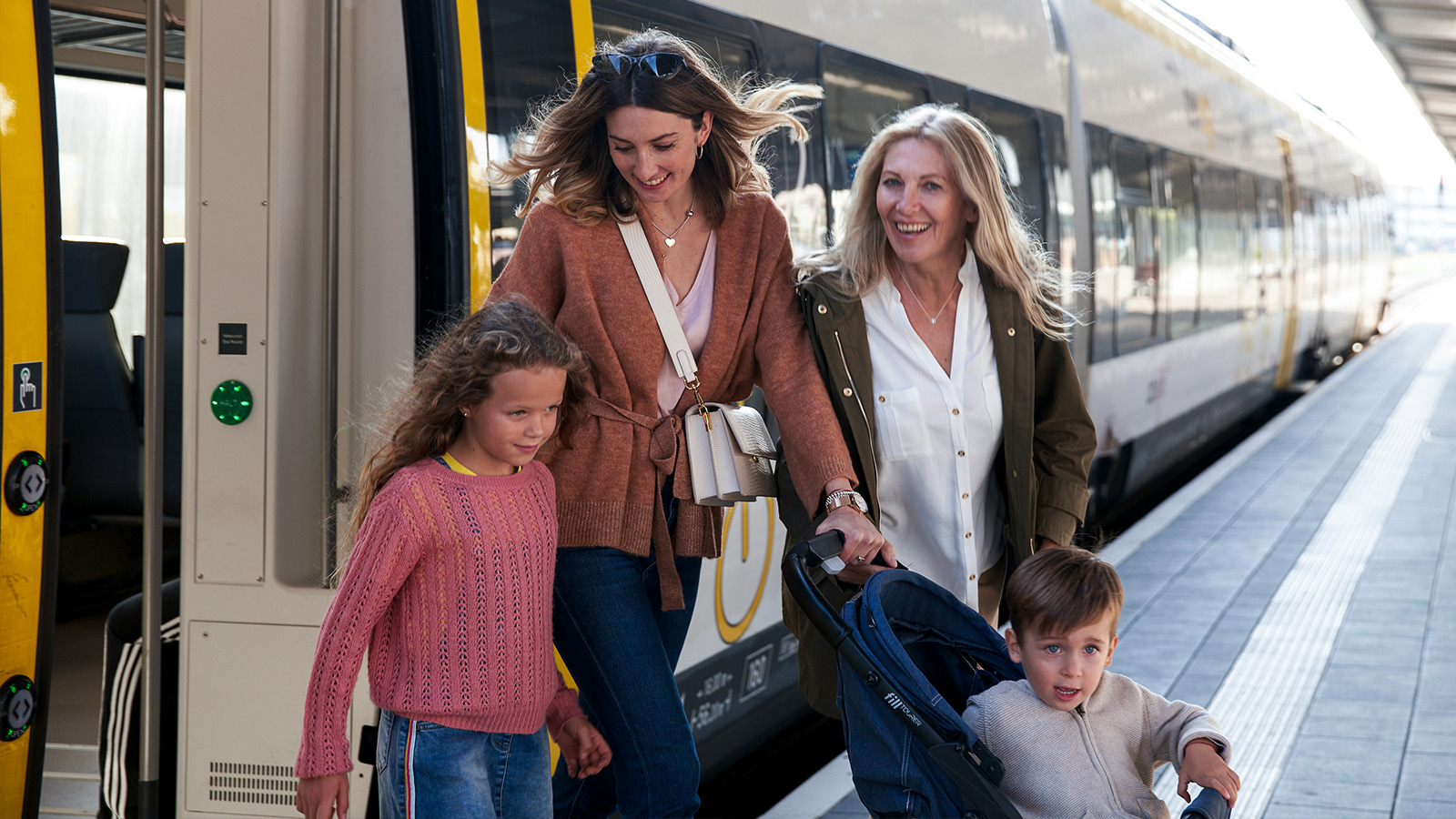 Eine Familie mit Kinderwagen steigt aus dem Zug