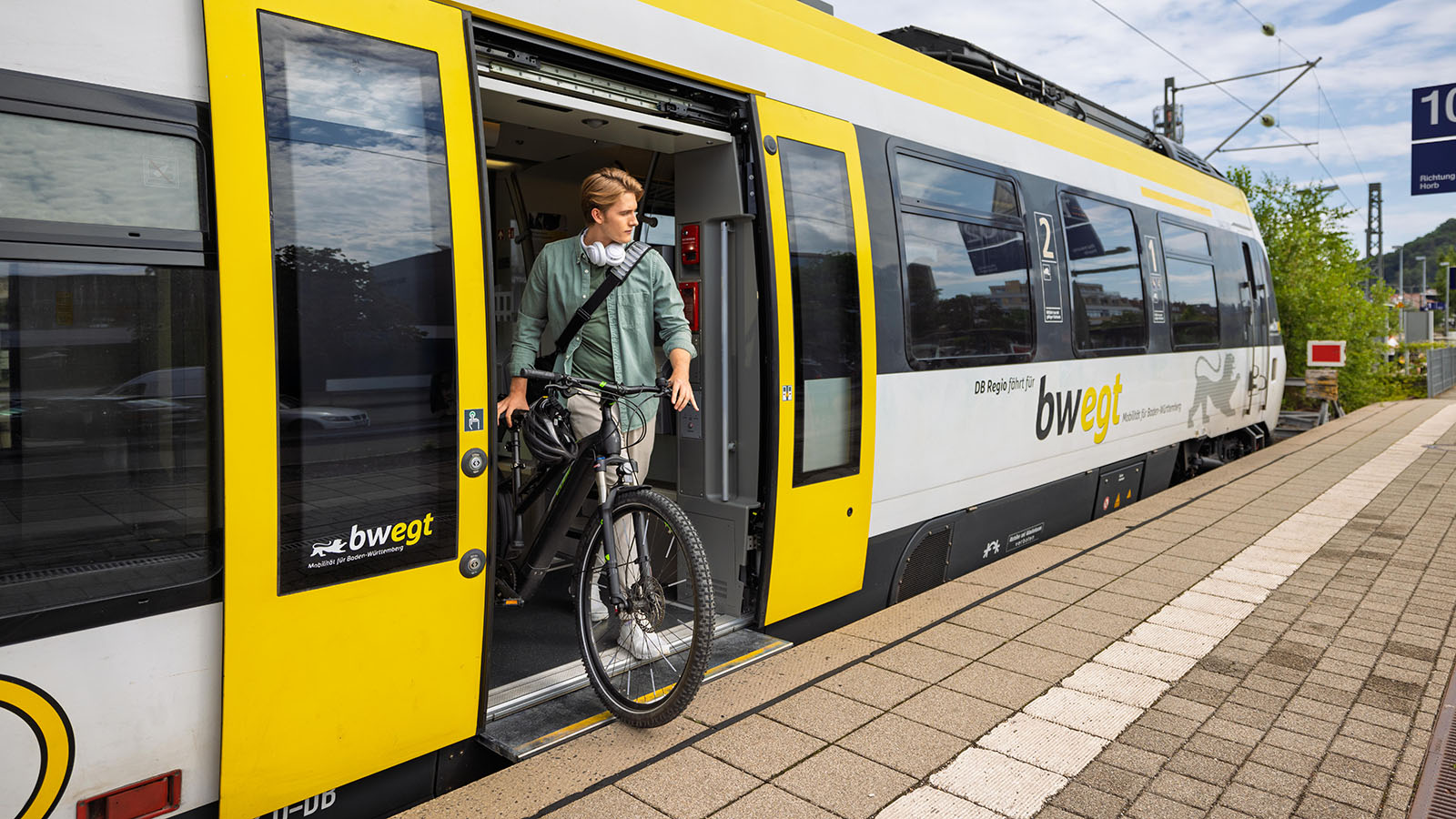 Aus dem bwegt-Zug steigt ein junger Mann mit seinem Fahrrad