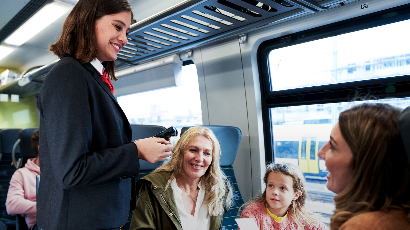 Bahnmitarbeiterin kommuniziert mit Fahrgästen