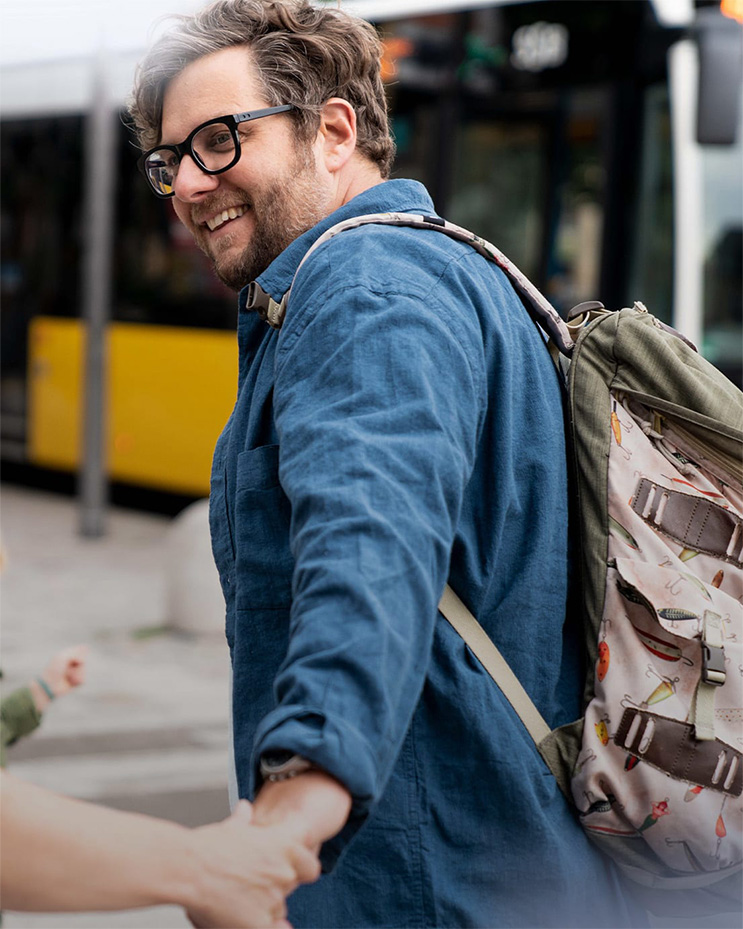 Ein Mann mit Rucksack steht in der Nähe von einem gelben Bus. 